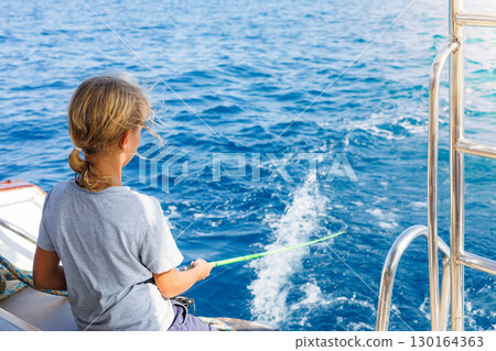 Child fishing from boat on ocean 130164363