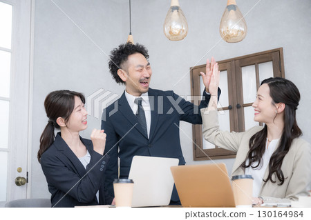 Multiple teams of male and female business people smiling and having a meeting, having fun at work and high-fiving for success 130164984