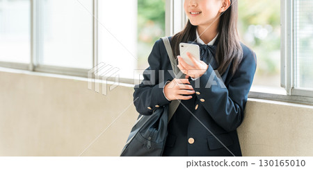 Smiling elementary school, junior high school, and high school girls using smartphones in the school hallway (crime prevention, safety, security) Smiling elementary school, junior high school, and high school girls using smartphones in the school hallway (crime prevention, safety, security) 130165010