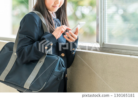 在學校走廊上微笑使用智慧型手機的小學、國中和高中女生(預防犯罪、安全、安心) 在學校走廊上微笑使用智慧型手機的小學、國中和高中女生(預防犯罪、安全、安心) 130165181