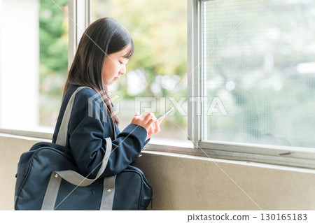 Smiling elementary school, junior high school, and high school girls using smartphones in the school hallway (depressed, lonely, alone) Smiling elementary school, junior high school, and high school girls using smartphones in the school hallway (depressed, lonely, alone) 130165183