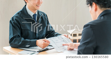 一位身著工作服的男銷售員和建築師使用藍圖解釋房產 130165580