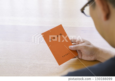 一名男子正在看他的退休金簿 一名男子正在看他的退休金簿 130166099