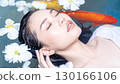 一位婦女在池塘裡沐浴，池塘裡有紅鯉遊動，還有漂浮的花朵 130166106