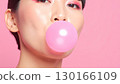 一位塗著粉紅色眼影的女士吹起了泡泡糖棒 130166109