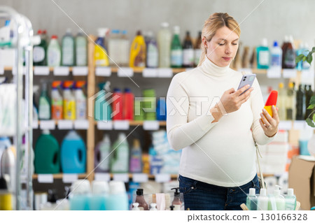 Pregnant shopper scanning barcode on sun lotion with phone 130166328