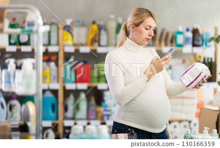 Pregnant woman scanning feminine pads in store 130166359
