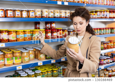 In Russian goods store, woman choose jar of pickled fermented cabbage In Russian goods store, woman choose jar of pickled fermented cabbage 130166469