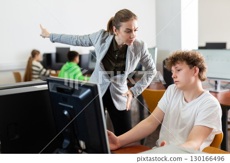 Teacher is dissatisfied with student during classes in the computer class of school Teacher is dissatisfied with student during classes in the computer class of school 130166496