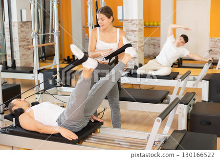Man athlete performs exercises to increase leg strength using sling reformer under coach guidance. Man athlete performs exercises to increase leg strength using sling reformer under coach guidance. 130166522