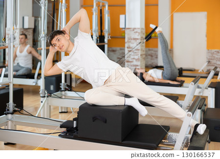 Man in different poses performs static and dynamic exercises on reformer 130166537