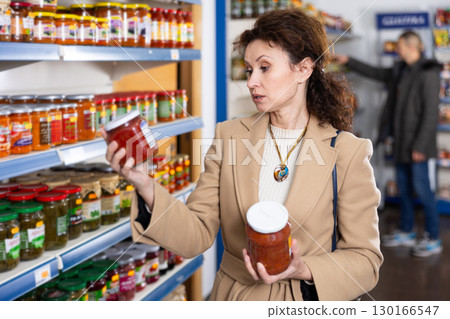 Woman shopper wants to buy a jar of delicious lecho in grocery store. 130166547