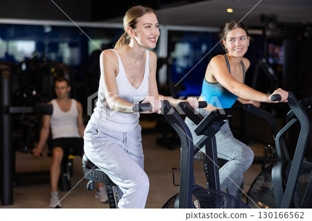 During classes on air bike, girls chat sweetly and smile 130166562