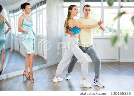 Couple in comfortable sports clothes waltz dancing during individual lesson Couple in comfortable sports clothes waltz dancing during individual lesson 130166586