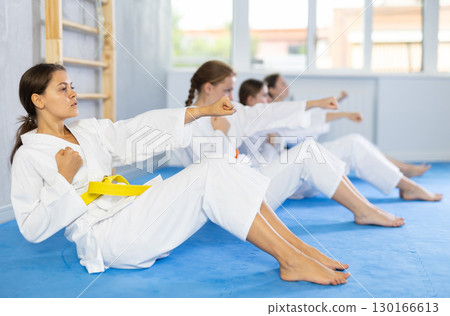 Girl athlete before martial match doing exercises to strengthen press and improve accuracy of hands 130166613