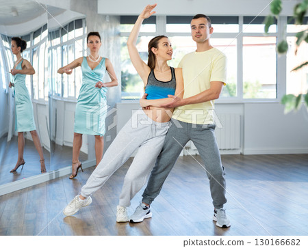 Positive couple practicing slow foxtrot in dance studio 130166682