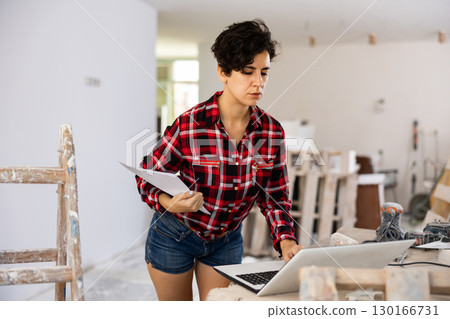 Female owner of the cottage checks the completion of repair work using laptop 130166731