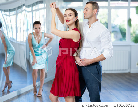 Man practicing samba with female partner in red in dance class 130166732