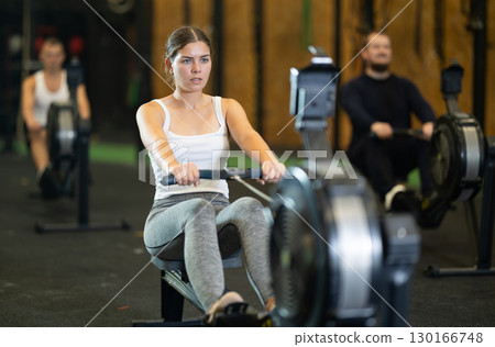 Sporty girl working out on rowing machine during functional training Sporty girl working out on rowing machine during functional training 130166748
