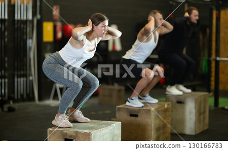 Sportive young girl squatting on box during crossfit workout 130166783
