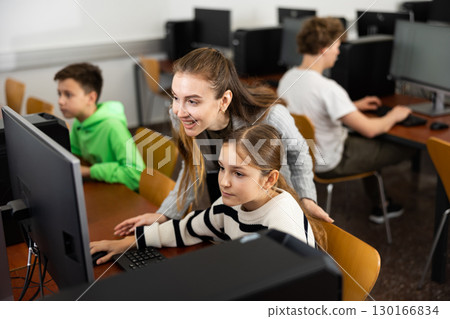 Positive woman teacher together with the girl teaches how to work on computer Positive woman teacher together with the girl teaches how to work on computer 130166834
