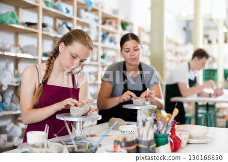 Teenage girl sculpts ceramic product in ceramic workshop 130166850