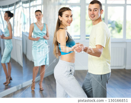 Couple in comfortable sports clothes waltz dancing during individual lesson Couple in comfortable sports clothes waltz dancing during individual lesson 130166851