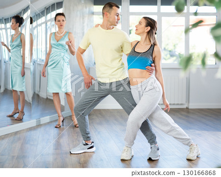Woman and man in sportswear performing tango at dance rehearsal 130166868