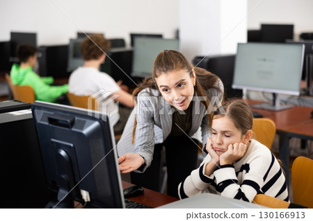 Teacher helping sad girl to solve computer problem 130166913