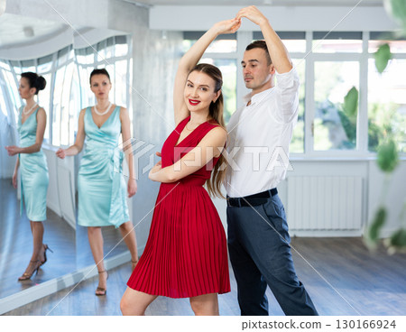 Man practicing samba with female partner in red in dance class Man practicing samba with female partner in red in dance class 130166924