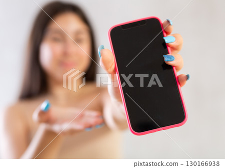Mobile phone held in hand against blurred background 130166938