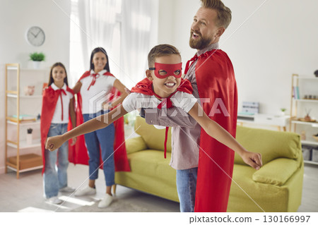 Happy smiling family of four in red super hero costumes playing game imagine flying at home. Happy smiling family of four in red super hero costumes playing game imagine flying at home. 130166997