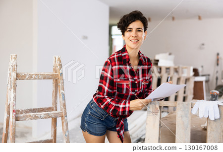 Portrait of woman filling documentation during repair works in construction site 130167008