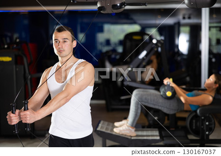 Active athlete young man during exercises on crossover exercise machine with loops and weighting 130167037