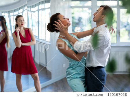 Coach, paired with man student, shows master class and explains technique of tango dance Coach, paired with man student, shows master class and explains technique of tango dance 130167038
