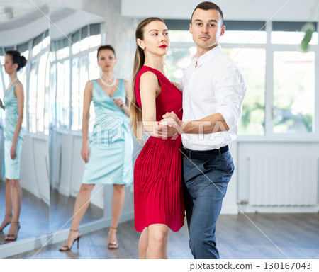 Couple in stage costumes learns tango dancing during individual lesson 130167043