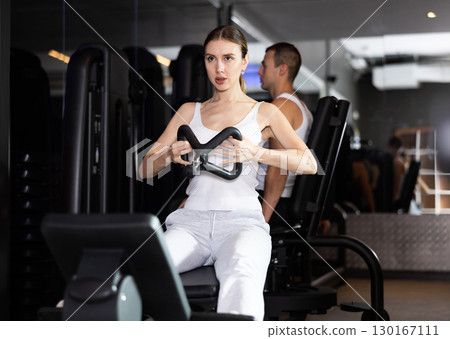 Girl pulls handle of simulator with effort during strength training Girl pulls handle of simulator with effort during strength training 130167111
