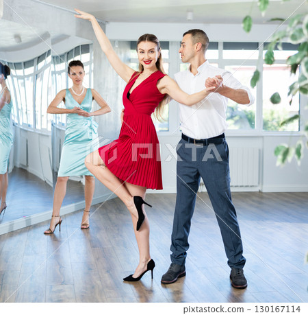 Couple in stage costumes learns tango dancing during individual lesson 130167114