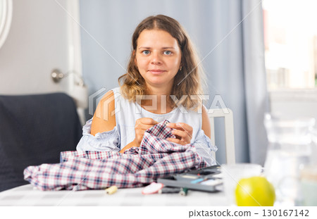 Woman repairing clothes with a needle and thread Woman repairing clothes with a needle and thread 130167142