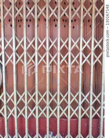 Wooden gate with lattice design and star shaped cutouts at top, set against reddish brown background, creating decorative and functional barrier 130167148