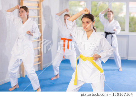 Teenage girl in kimono practicing punches and blocks during martial arts training Teenage girl in kimono practicing punches and blocks during martial arts training 130167164