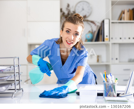 Female cleaning service worker wiping working table in office Female cleaning service worker wiping working table in office 130167206