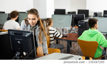 Interested young woman studying in university computer lab 130167285