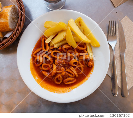 Calamari rings braised in American sauce with fries Calamari rings braised in American sauce with fries 130167302