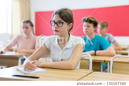 Portrait of positive teenage schoolgirl sitting on lesson Portrait of positive teenage schoolgirl sitting on lesson 130167380