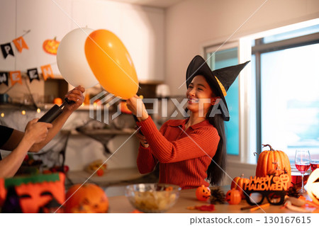 Halloween Joy. Woman in witch hat enjoying playful balloon interaction. 130167615