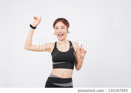 Dance is in her soul while she trains with headphones in a focused routine. Her body feels alive, and she smiles as she starts to dance once more. isolated studio white background 130167895