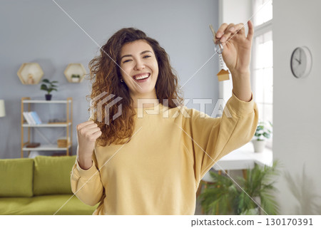 Portrait of a young happy smiling pretty woman with keys in her hands standing at home. Portrait of a young happy smiling pretty woman with keys in her hands standing at home. 130170391