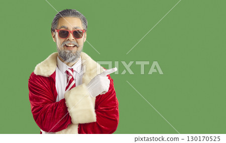 Glad male Santa Claus dressed in red clothing indicating index finger on copy space 130170525