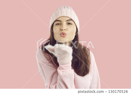 Beautiful romantic woman in warm fur mittens gently blows an air kiss to camera. 130170526